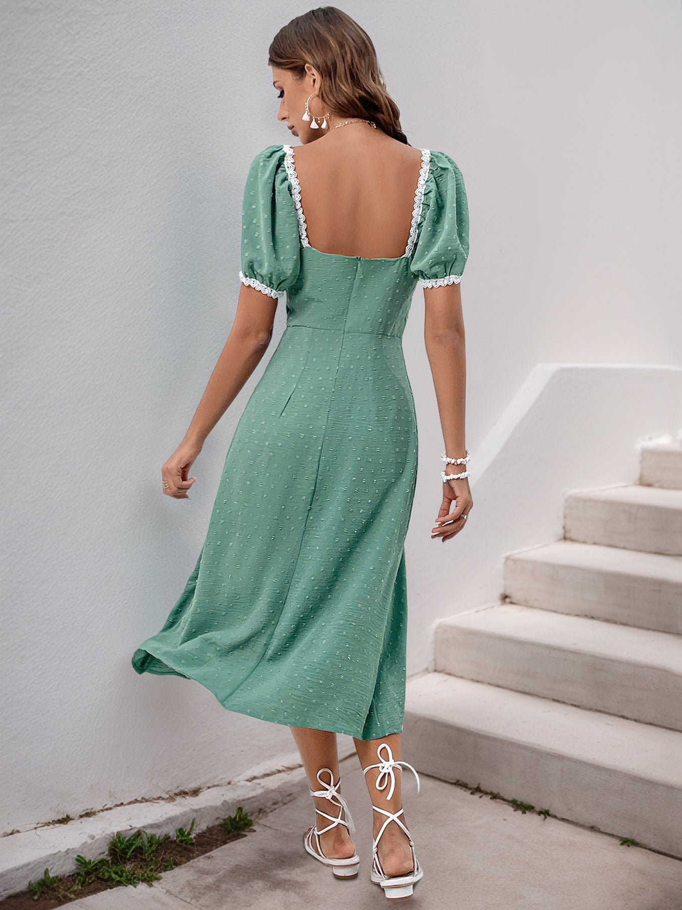 Back view of green puff sleeve dress with lace trim and fitted waist.