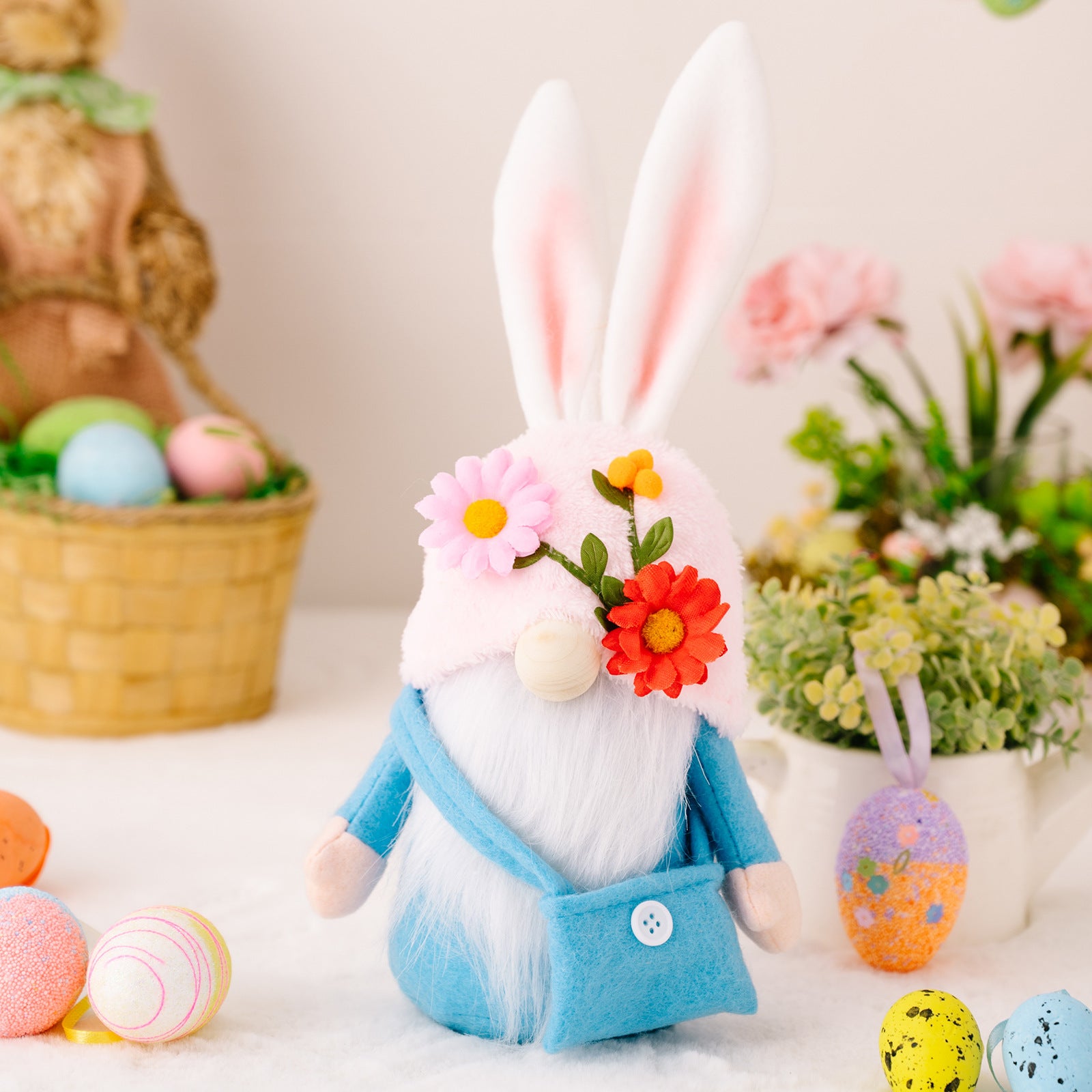 A blue-dressed bunny gnome with a felt crossbody bag, white beard, and floral hat, surrounded by pastel-colored Easter decorations.