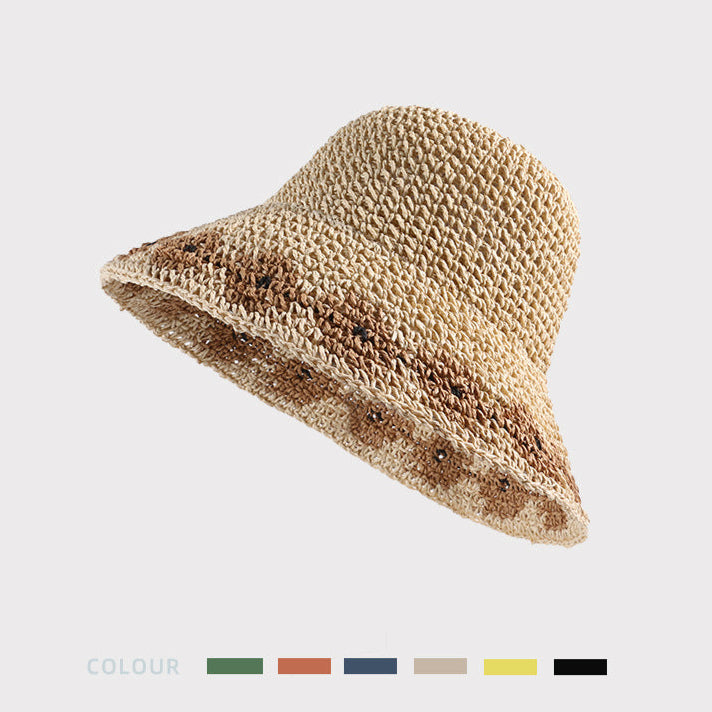 A close-up of a beige woven bucket hat with a brown floral pattern, showcasing the texture and woven details on a neutral background.