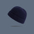 A navy blue ribbed knit beanie with folded cuff floating against slate gray background, showing detailed fisherman style texture