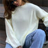 Close-up of cream ribbed knit sweater detail, paired with jeans and black sunglasses, showing textured stitch pattern