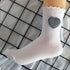 White crew sock with ruffle trim and gingham heart patch against grid background