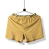Yellow boxer short with branded elastic waistband displayed on hanger against white background