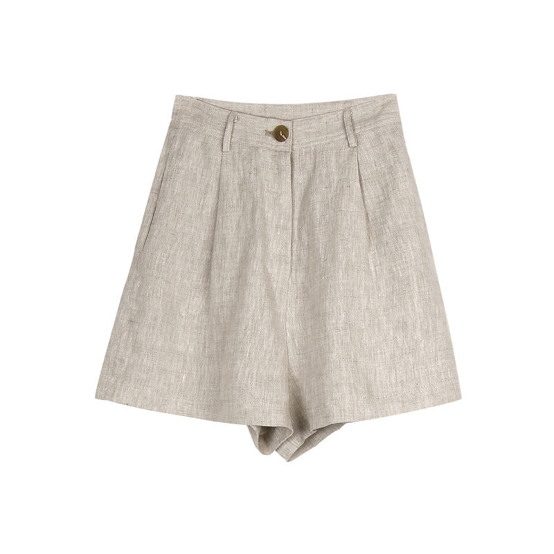 Product shot of beige linen shorts with pleated front, side pockets, and brass button closure on white background