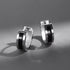 Product photo of silver huggie hoop earrings pair with black center stripe on gray background