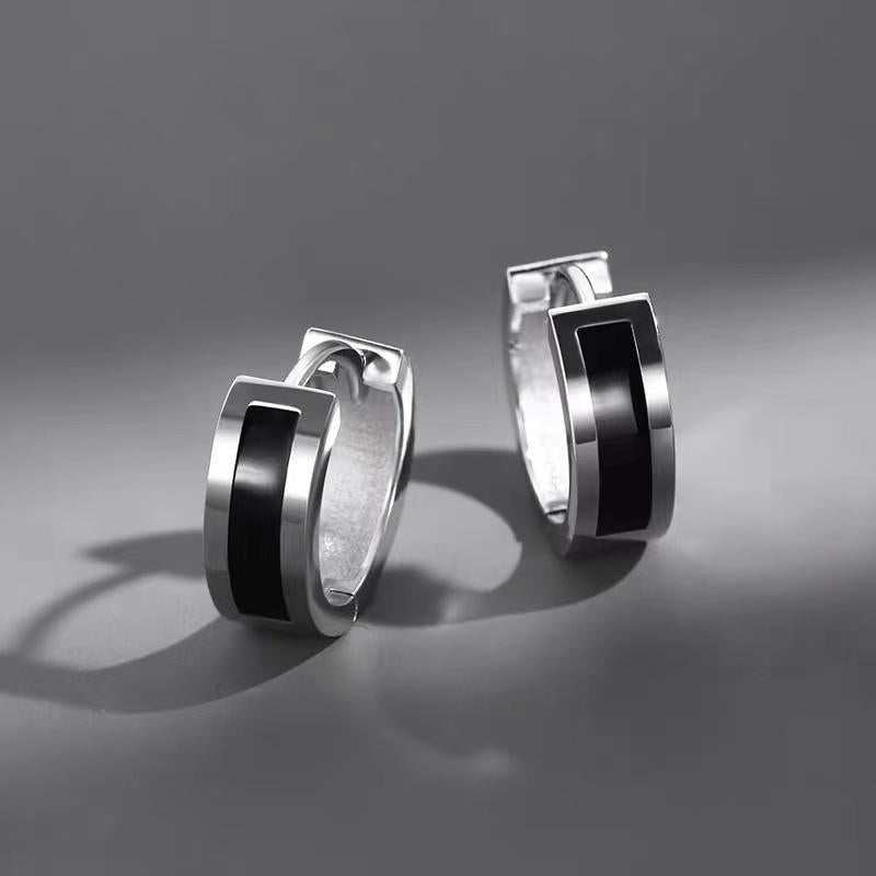 Product photo of silver huggie hoop earrings pair with black center stripe on gray background