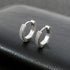 Pair of silver tone pave crystal huggie hoop earrings displayed on black leather surface, showing detailed small stone setting