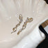 Minimalist silver bow earrings with curved ribbons shown on white ceramic display, highlighting clean lines