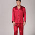 Man wearing burgundy red silk pajama set with contrast piping and chest pocket against neutral background