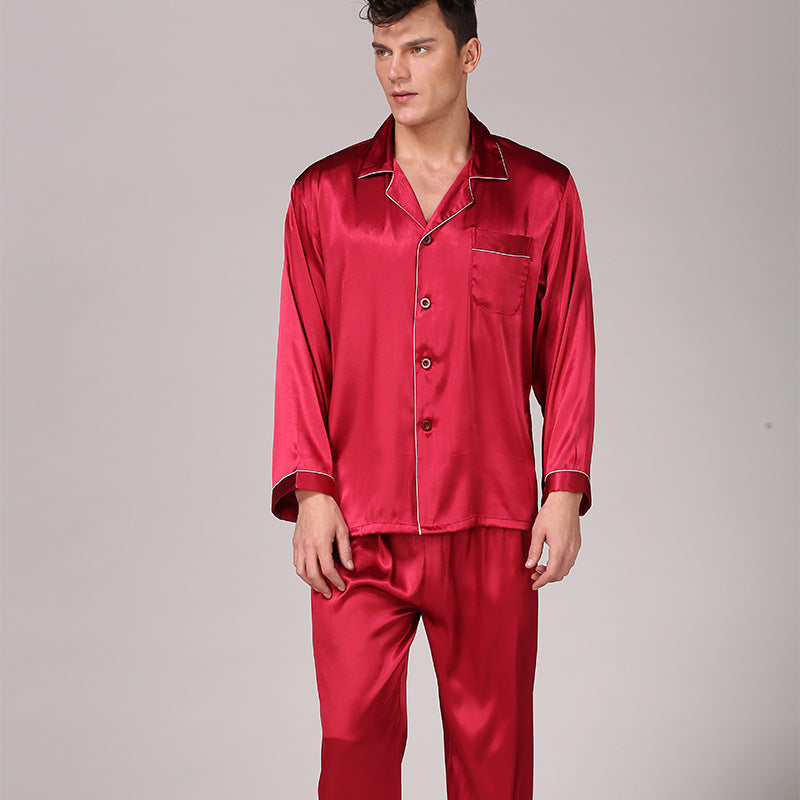 Man wearing burgundy red silk pajama set with contrast piping and chest pocket against neutral background