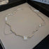 Silver necklace with organic links, pearls, and a square gemstone pendant in a jewelry box