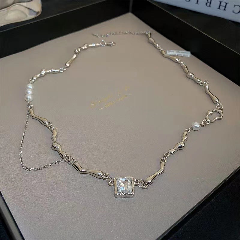 Silver necklace with organic links, pearls, and a square gemstone pendant in a jewelry box