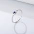 Silver ring with blue sapphire in eye-shaped setting against white backdrop