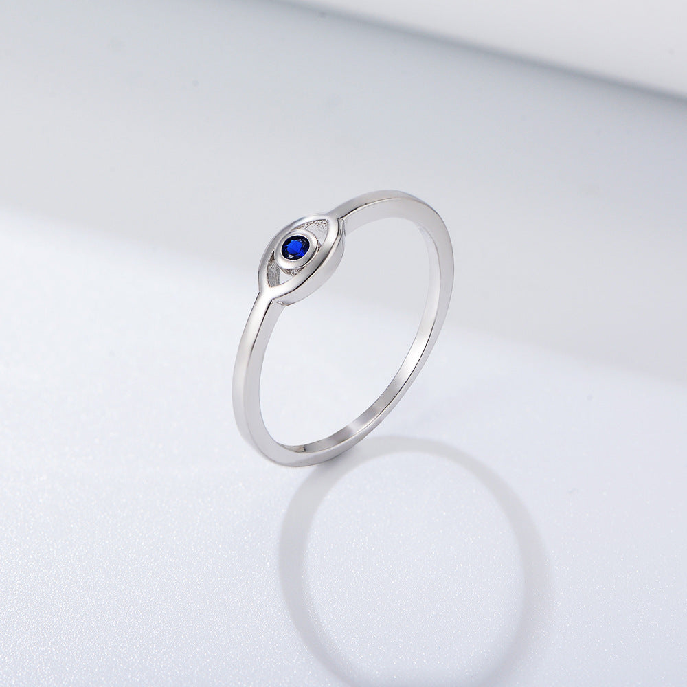 Silver ring with blue sapphire in eye-shaped setting against white backdrop