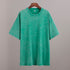 Green t-shirt on a wooden hanger against a gray background