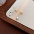 Silver teardrop earrings with gold ball studs on textured background