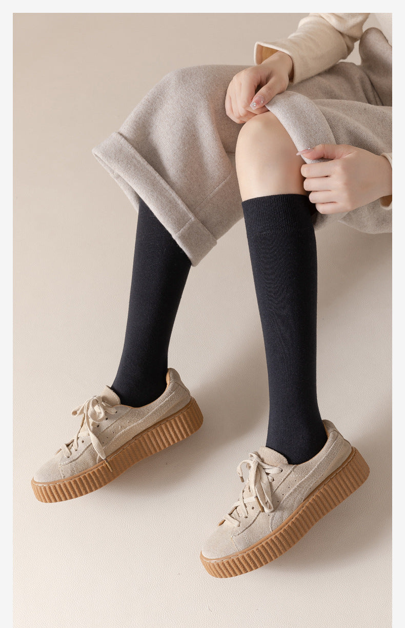 Person sitting in beige outfit with black knee-socks and beige platform sneakers