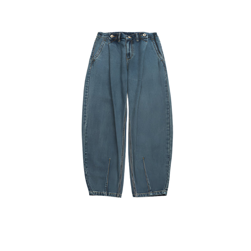 Product shot of balloon-fit medium-wash denim jeans with three-button waistband, wide legs and vertical seam detail on white background
