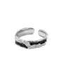 A silver open-ended ring with a black enamel wave design and a textured, rugged finish