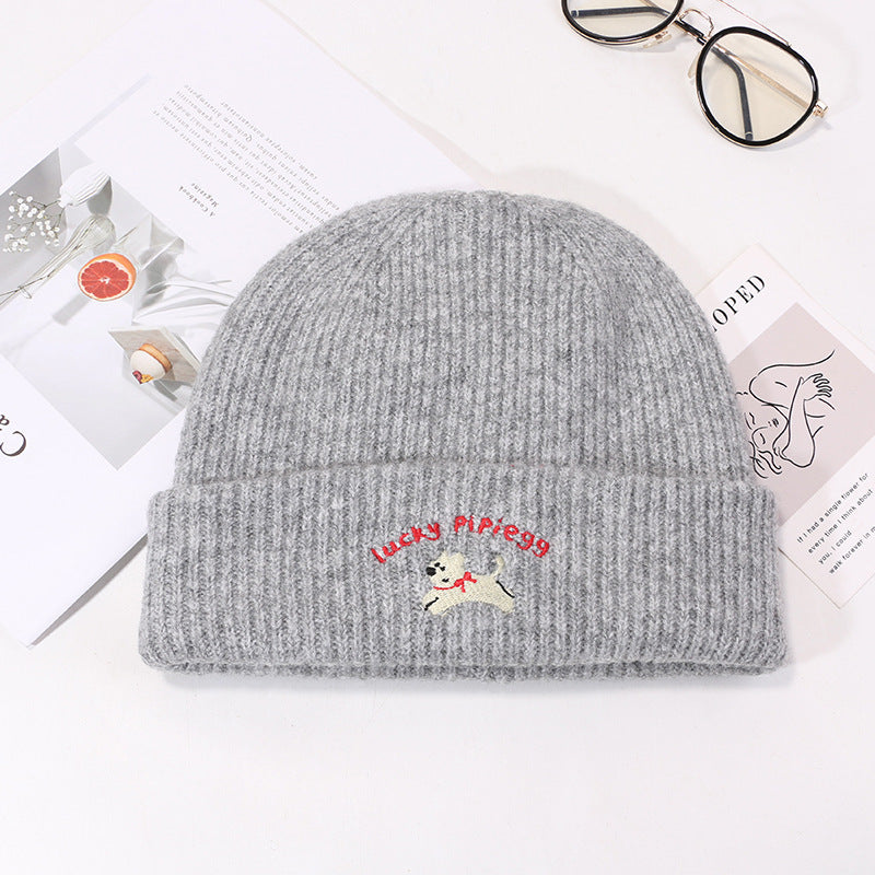 Light gray knit beanie featuring jumping puppy logo and red branding