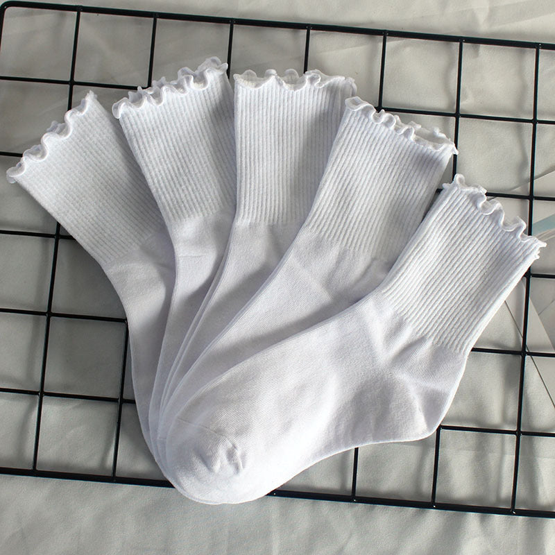 Fan display of five white ruffle-trim ankle socks arranged on black grid rack, showing frilled edge detail and ribbed cotton texture