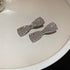  Rhinestone bow-shaped hair clips with a silver-tone finish, featuring a sparkling crystal design, placed on a plate.