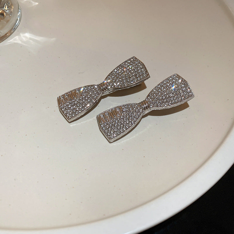  Rhinestone bow-shaped hair clips with a silver-tone finish, featuring a sparkling crystal design, placed on a plate.
