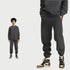 Man with afro hairstyle in charcoal sweatsuit. Close-up shows jogger fit with brown and cream Jordan sneakers