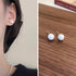 Side-by-side images of pearl stud earring worn on ear and displayed on wooden surface