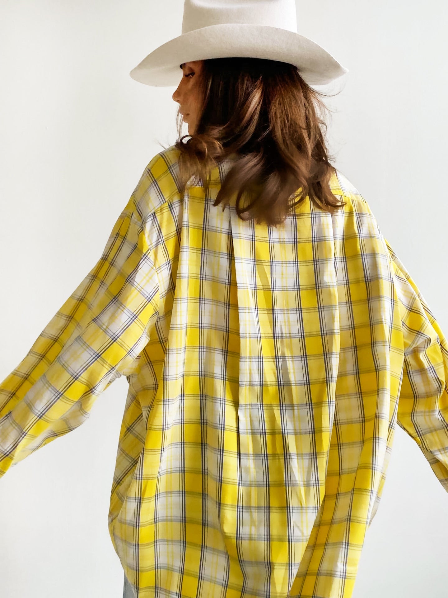 Back view of yellow plaid shirt with white cowboy hat, showcasing relaxed fit