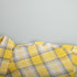 Curved edge of yellow plaid shirt fabric with intersecting check lines