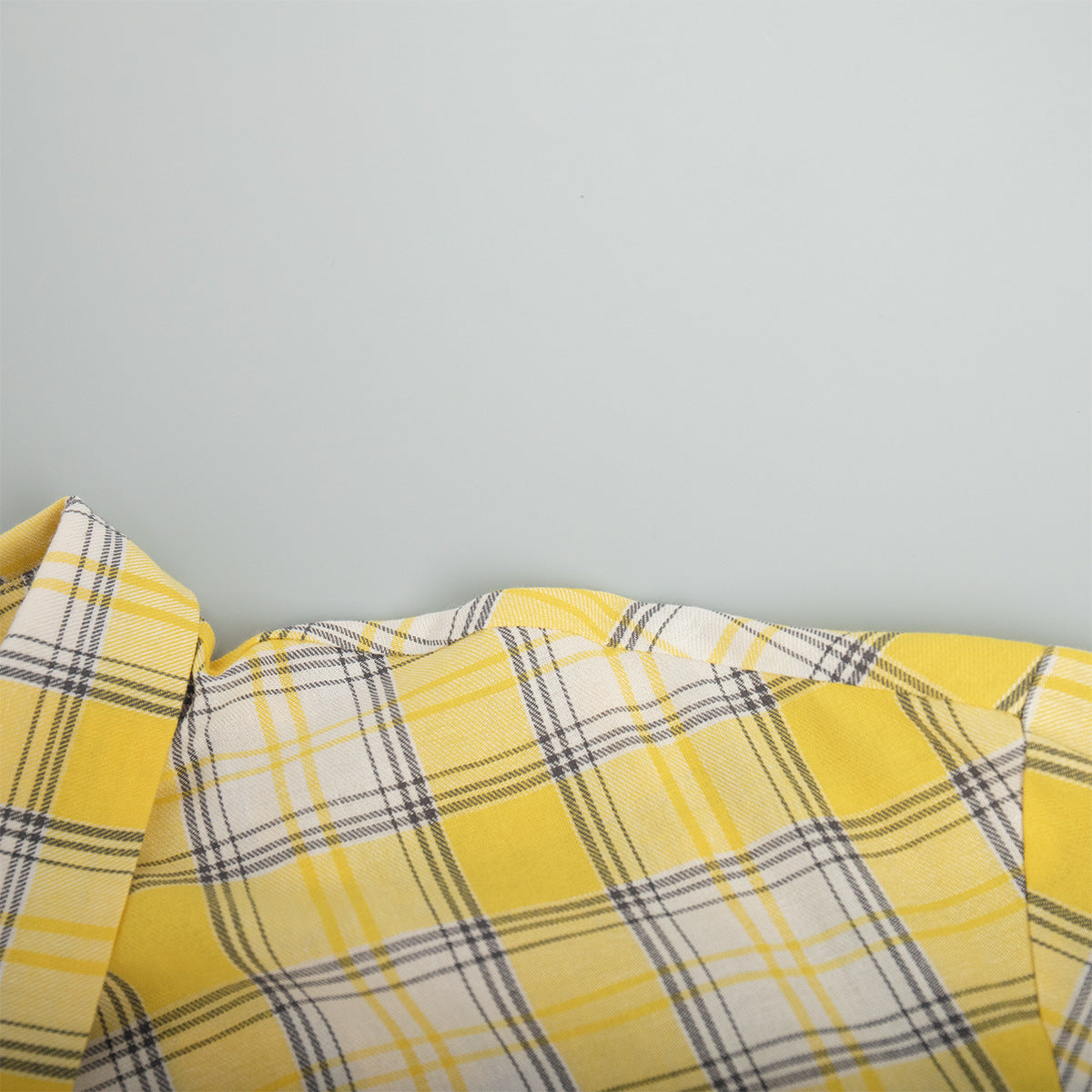 Curved edge of yellow plaid shirt fabric with intersecting check lines