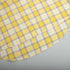 Curved edge of yellow plaid shirt with distinct check design