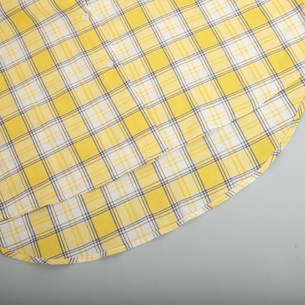 Curved edge of yellow plaid shirt with distinct check design