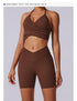 Woman in chocolate brown wrap halter crop top and matching biker shorts, styled with white sneakers