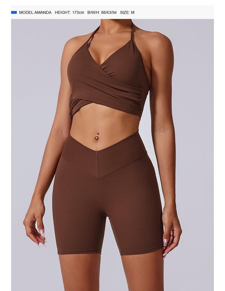 Woman in chocolate brown wrap halter crop top and matching biker shorts, styled with white sneakers