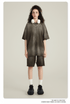 Model wearing olive green oversized t-shirt with matching shorts, white headphones, silver necklace, white socks and black chunky sneakers against neutral background