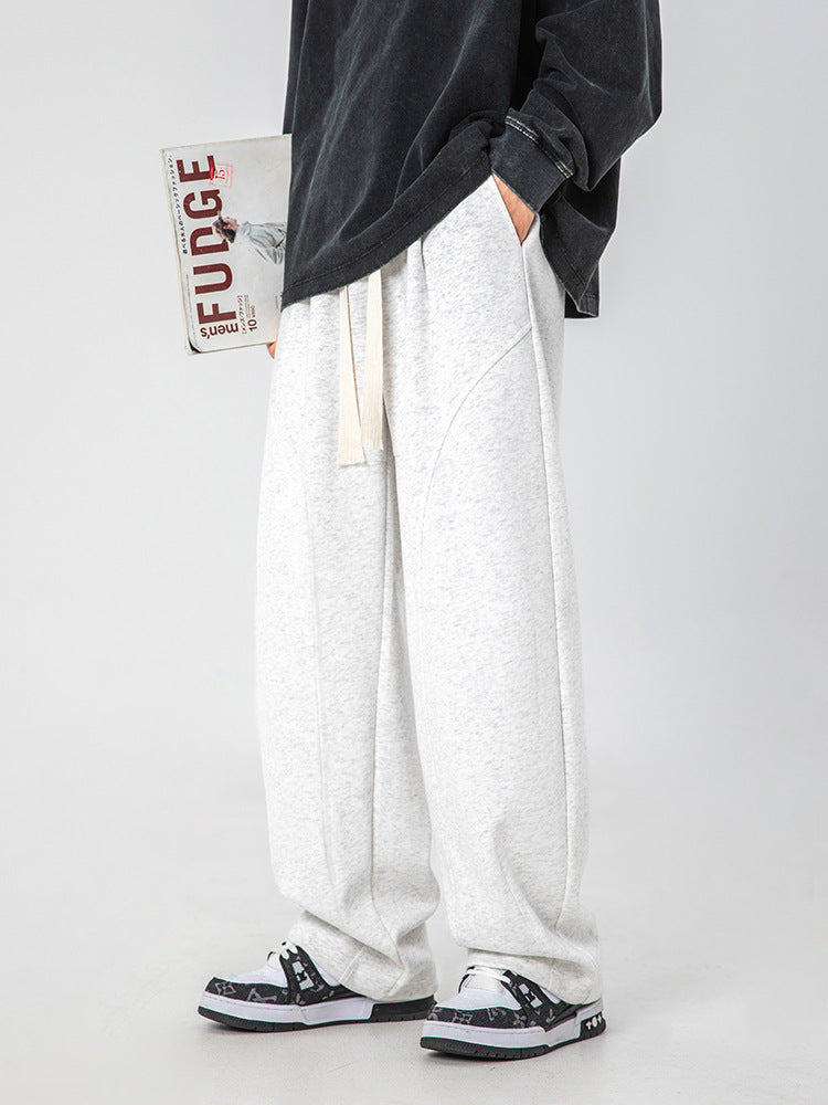 A model wearing oversized black sweatshirt and wide-leg heather gray sweatpants with drawstring waist, standing against light background