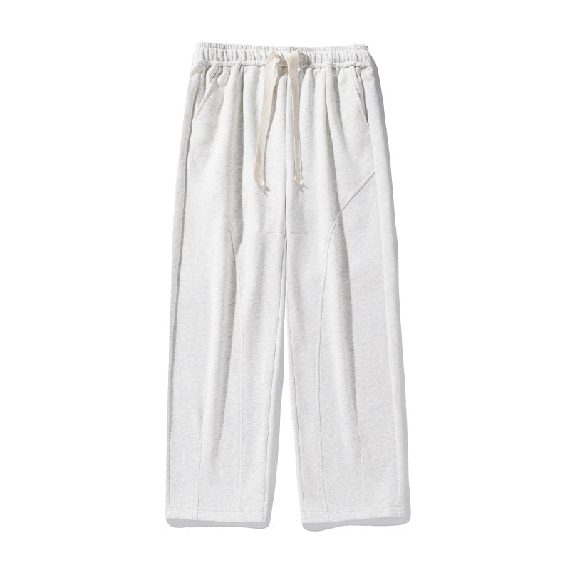 A model is standing in white wide-leg lounge pants with elastic waistband, drawstring closure and diagonal seam details on a plain background