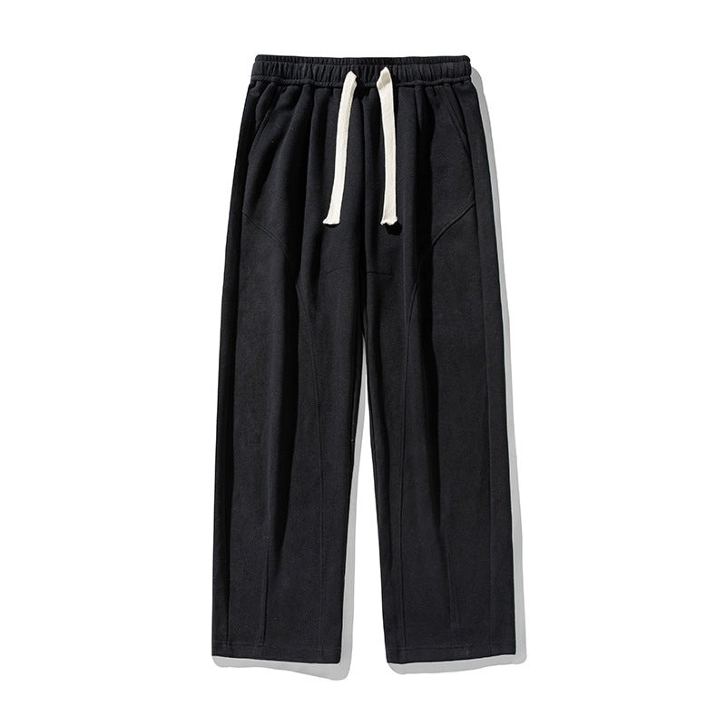 A model is showcasing black wide-leg sweatpants with white drawstring, elastic waistband and angular seam construction against a white backdrop