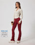 A woman standing in cream ribbed top with v-neck collar and burgundy ruched leggings, holding coffee cup against white background. Model Mali, 175cm, size S