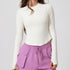 A model is wearing a cream half-zip crop top with long sleeves paired with lilac joggers. Clean lines with minimalist design against white background