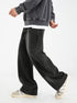 A model walking in black wide-leg denim jeans with visible seams, gray sweatshirt over white tee, paired with retro white and gray sneakers against white background