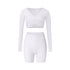 White athletic wear with long sleeve wrap top and fitted shorts, showing clean lines and minimal design