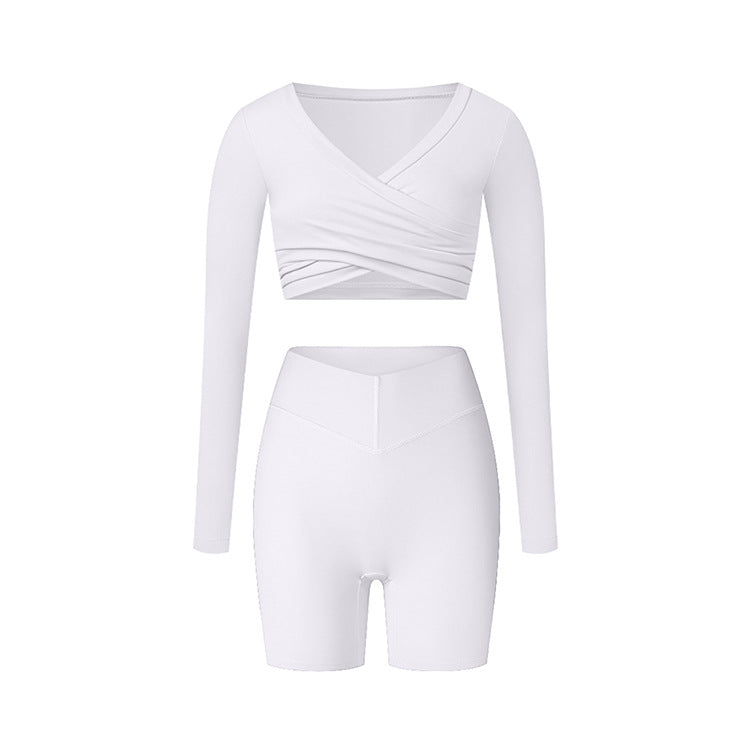 White athletic wear with long sleeve wrap top and fitted shorts, showing clean lines and minimal design