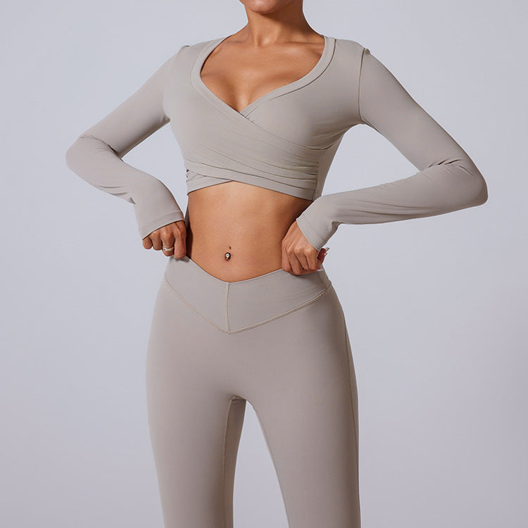 Gray workout set with wrap-style crop top and high-waisted flared pants, showing v-neck and ruched front details