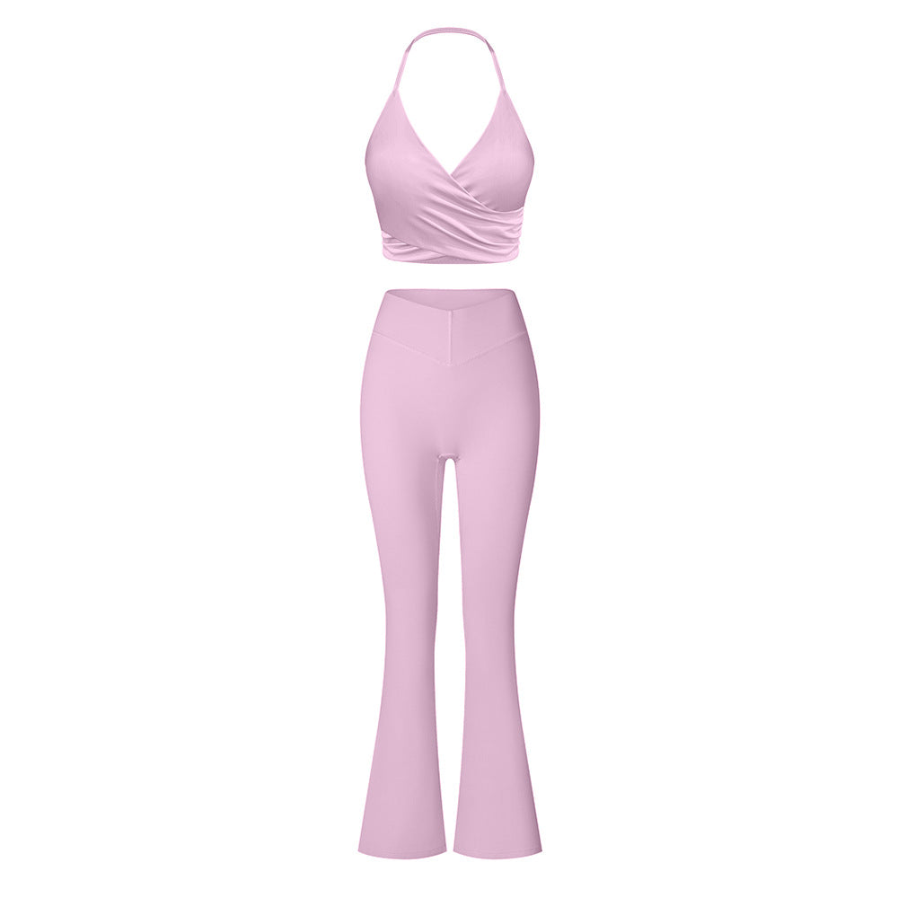Pastel pink two-piece workout set: halter neck sports bra with wrap detail and flared yoga pants with high-waisted v-shaped waistband