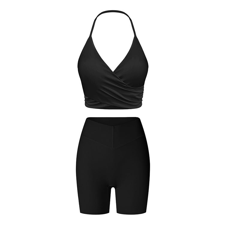Black workout set with halter neck sports bra featuring wrap detail and high-waisted compression shorts