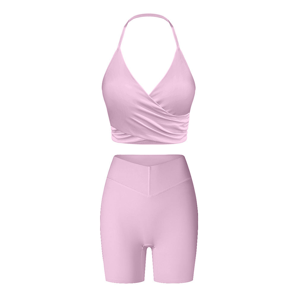 Pink workout set combining wrap-style halter top and high-waisted compression shorts