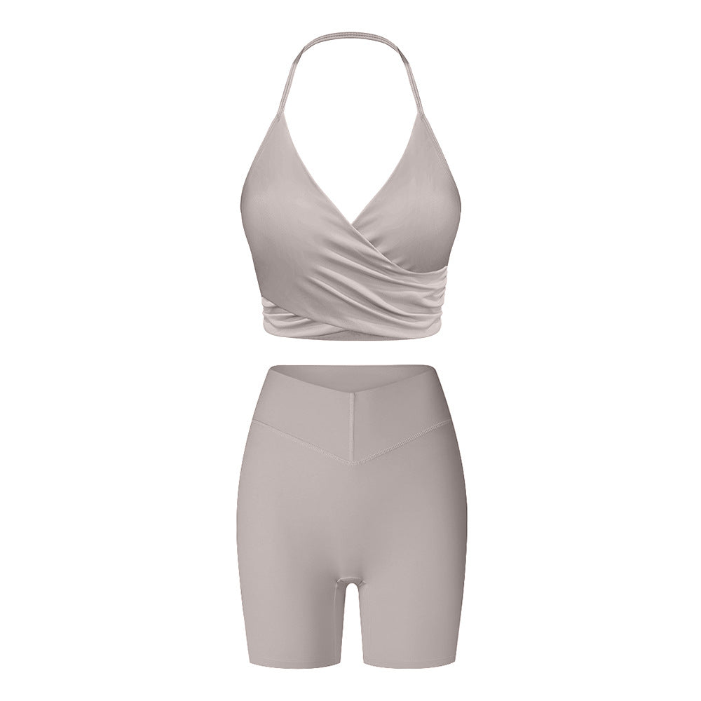 Gray workout set with halter wrap sports bra and high-waisted compression shorts